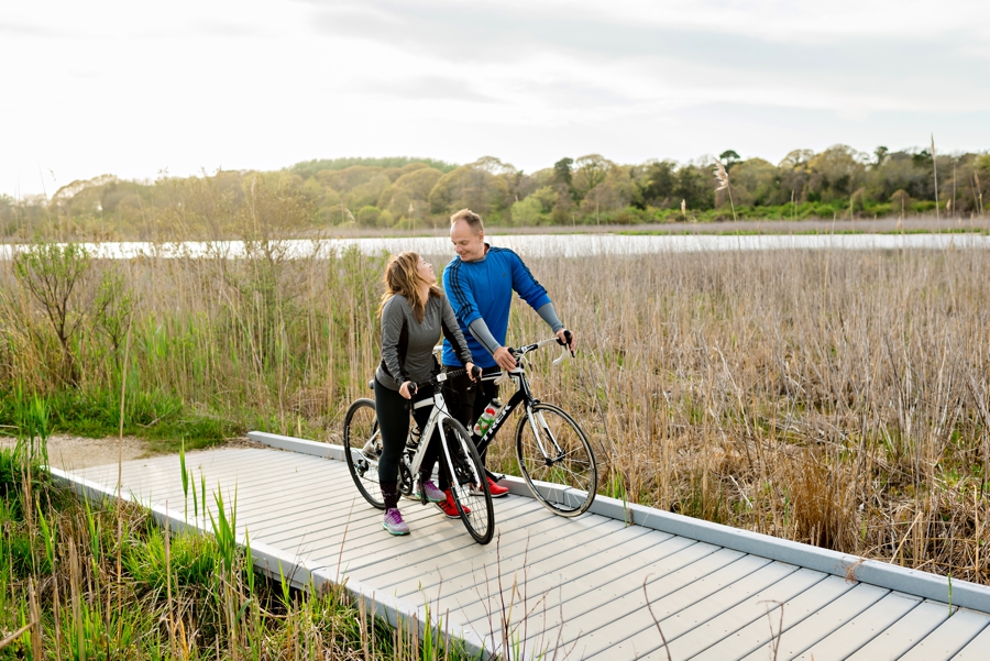 A fun couple ride bikes on the boardwalk in cape may.